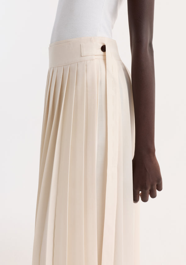 Close-up of a Plissé wrap skirt in cream, highlighting its pleated design, wide waistband with tab and button, worn by a model.