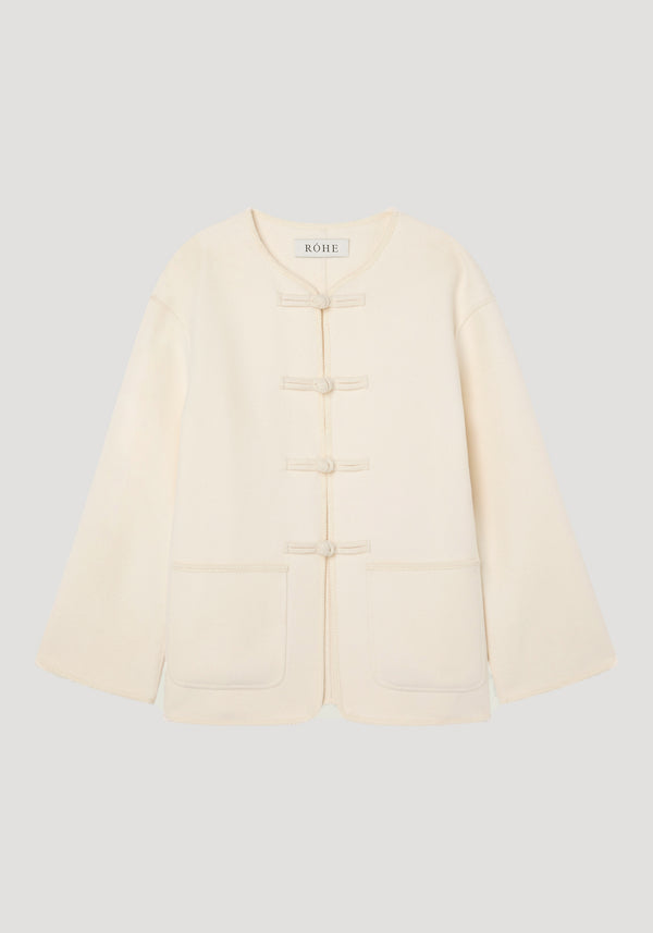 Double-faced wool pankou jacket in off-white with frog toggles, large patch pockets, embroidered edges, showcasing a minimalist design by RŌHE.