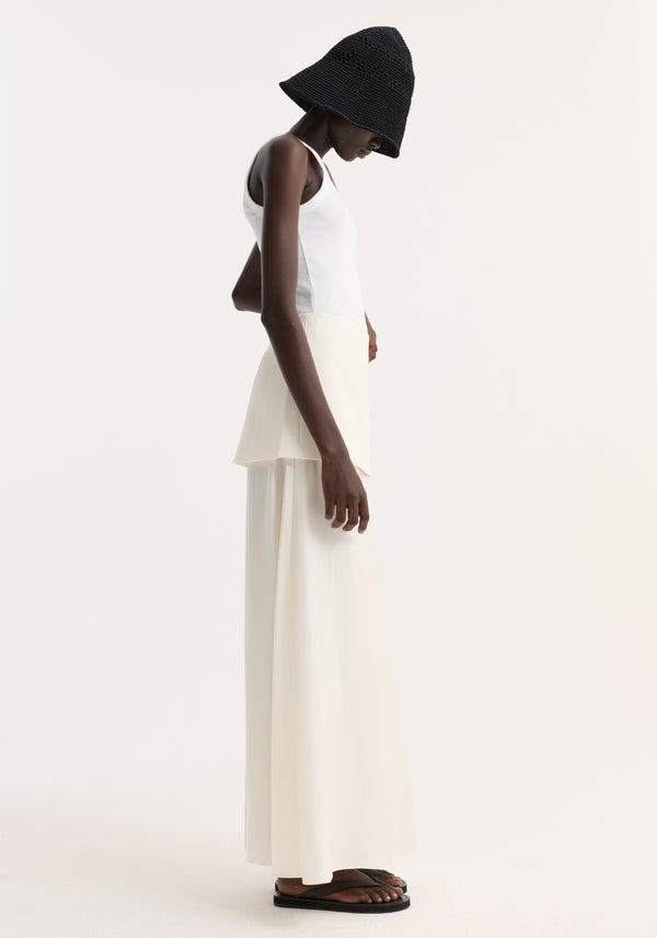 Model wearing Integrated fluid silk skirt | cream, showcasing high waist, layered panels, and flowing silhouette. Paired with a ribbed tank and crocheted bucket hat.