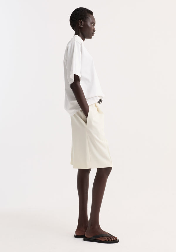 Model wearing Oversized cotton t-shirt in optic white with a crew neck and drop shoulder, tucked into loose shorts, showcasing a casual, relaxed fit.