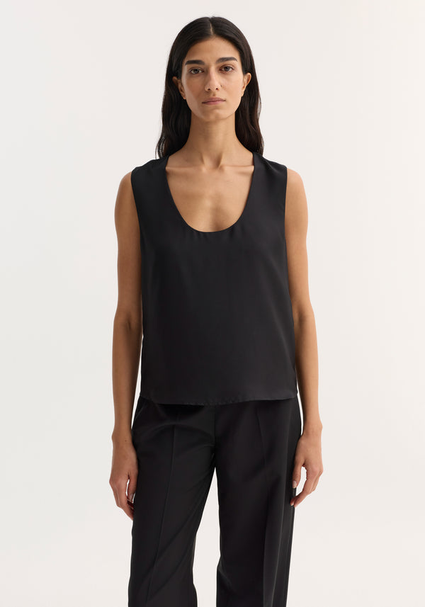 Scoop-neck silk top in black, worn by a model. Features wide scoop neckline and loose fit. Made from 100% silk, ideal for minimalist layering.