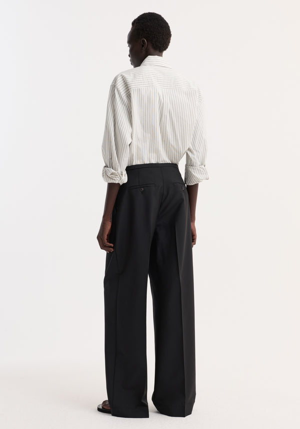 Person wearing Relaxed drawstring trousers | black, featuring a wide-leg fit, drawstring waistband, front pleats, and back welt pockets, styled with a striped shirt.