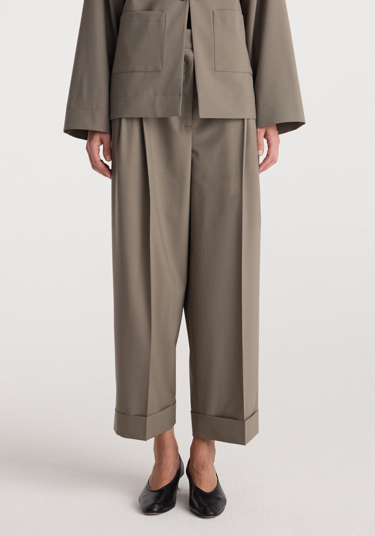 High-waist turn-up trousers | taupe shown on a model wearing black pointed-toe shoes, featuring wide straight legs and a relaxed fit with cuffed hems.