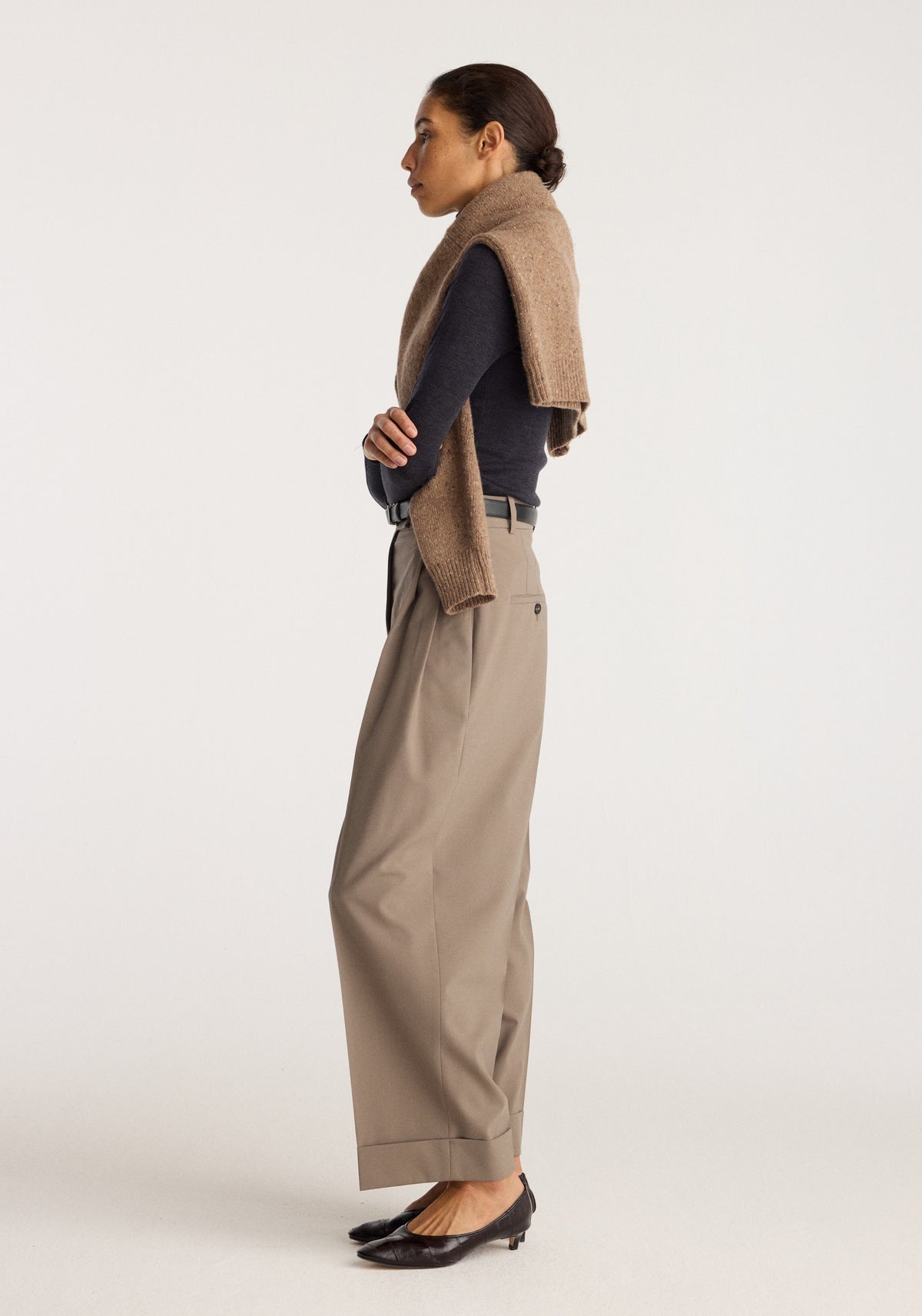 High-waist turn-up trousers | taupe shown in side view on a model with a relaxed fit and folded cuffs styled with a dark top and loafers