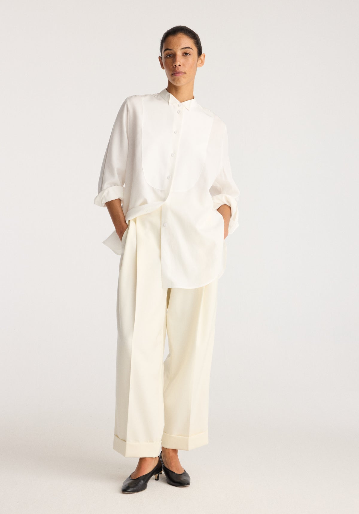 High-waist turn up trousers | off white on a model styled with a white shirt and black flats showing the high waist and turned up hems