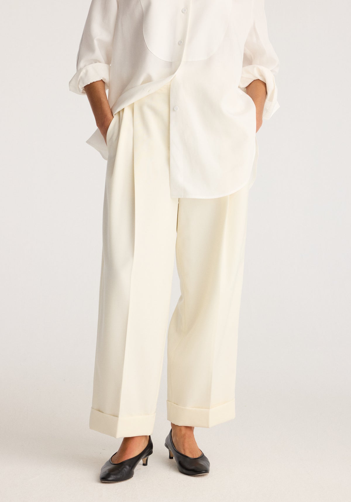 High-waist turn up trousers | off white worn with a loose white shirt showing cuffed hems and straight legs styled with black low heel shoes