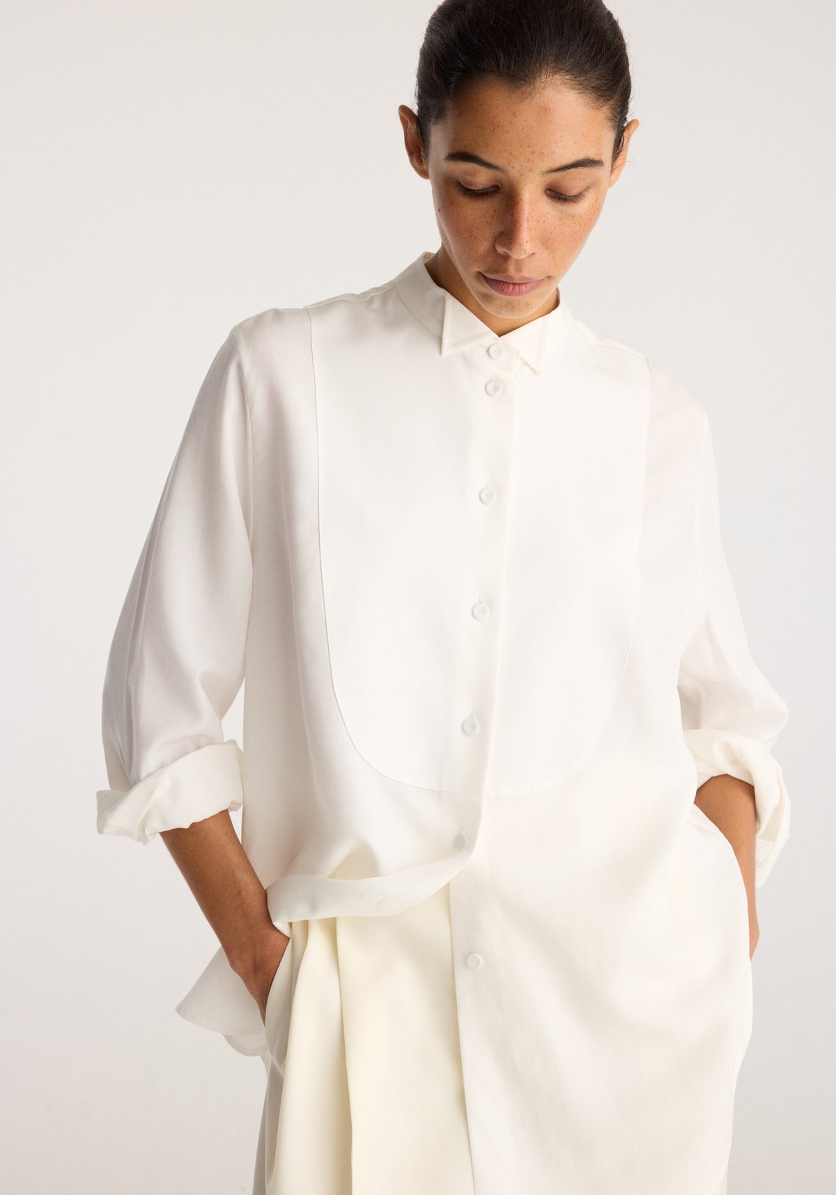 Tuxedo shirt | optic white worn by a model, featuring a high collar, concealed front buttons, long sleeves, and a relaxed fit with side pockets