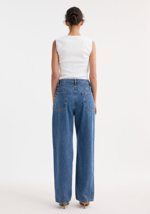 Back view of a person in Signature baggy fit denim, mid denim blue, featuring wide-leg, low-waist jeans, white tank top, and nude heeled sandals.