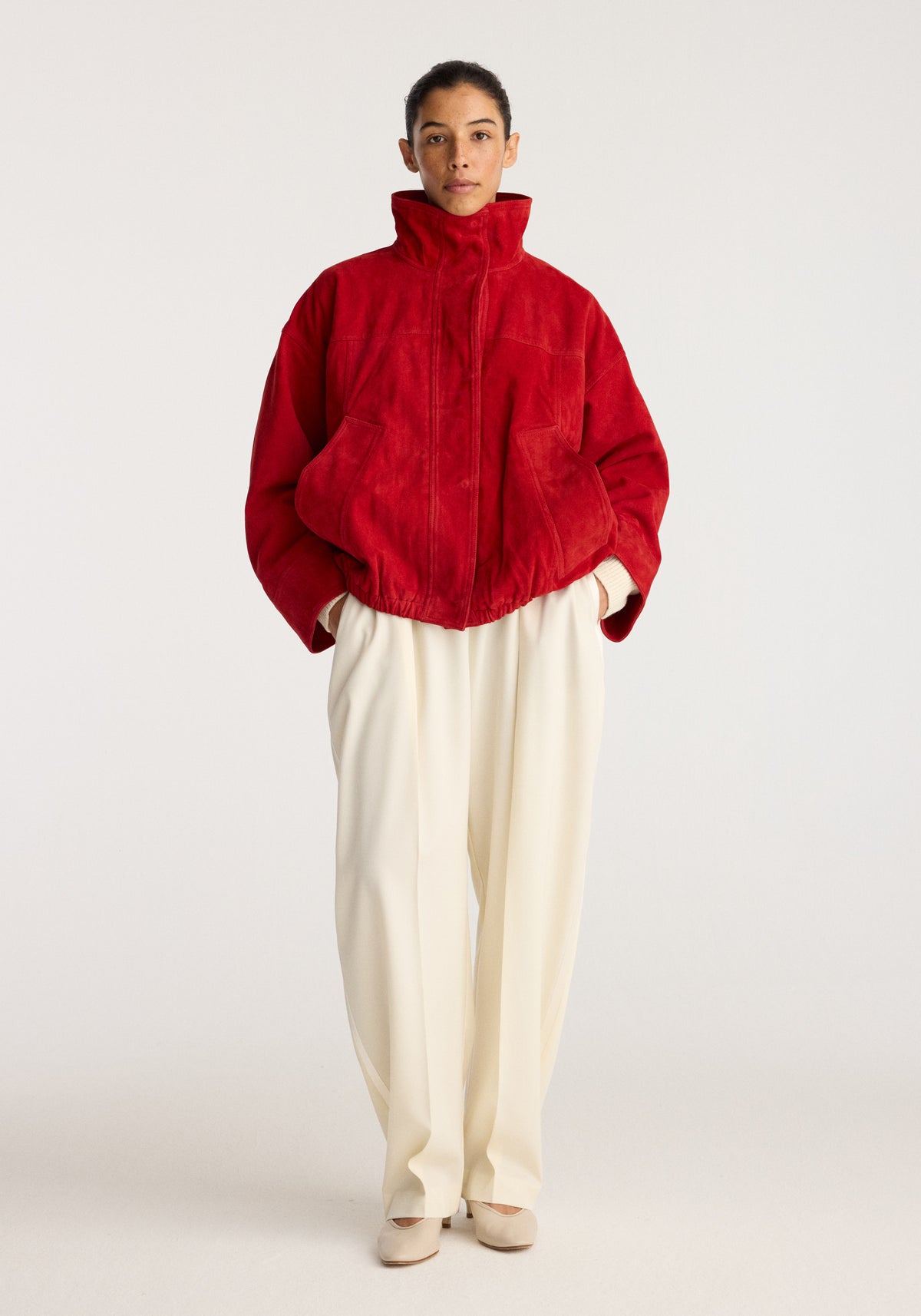 Reinvented suede jacket | red worn by a model with a high collar, front zip closure, relaxed fit, long sleeves, and gathered hem.