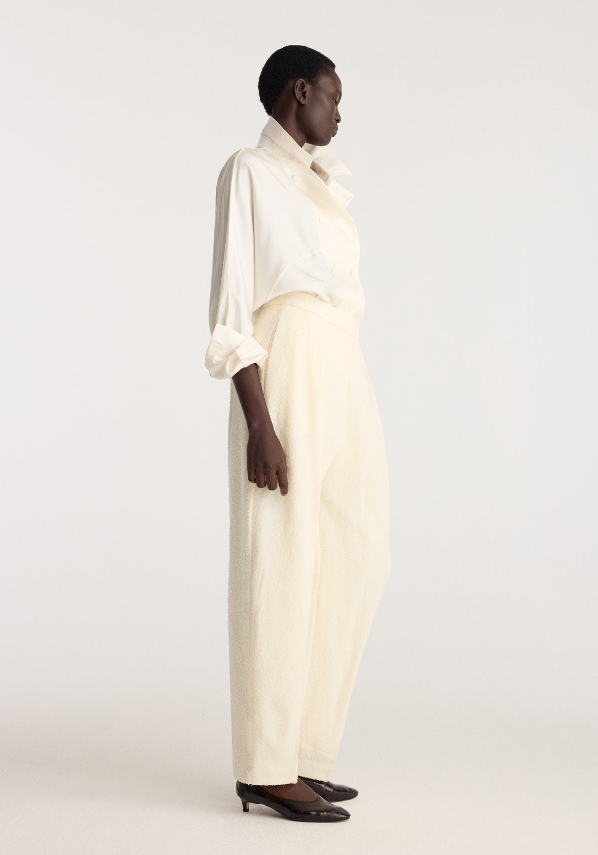 Double breasted silk top | cream modeled in profile with a relaxed fit, long sleeves, pointed collar, and softly gathered waist in an ivory cream shade