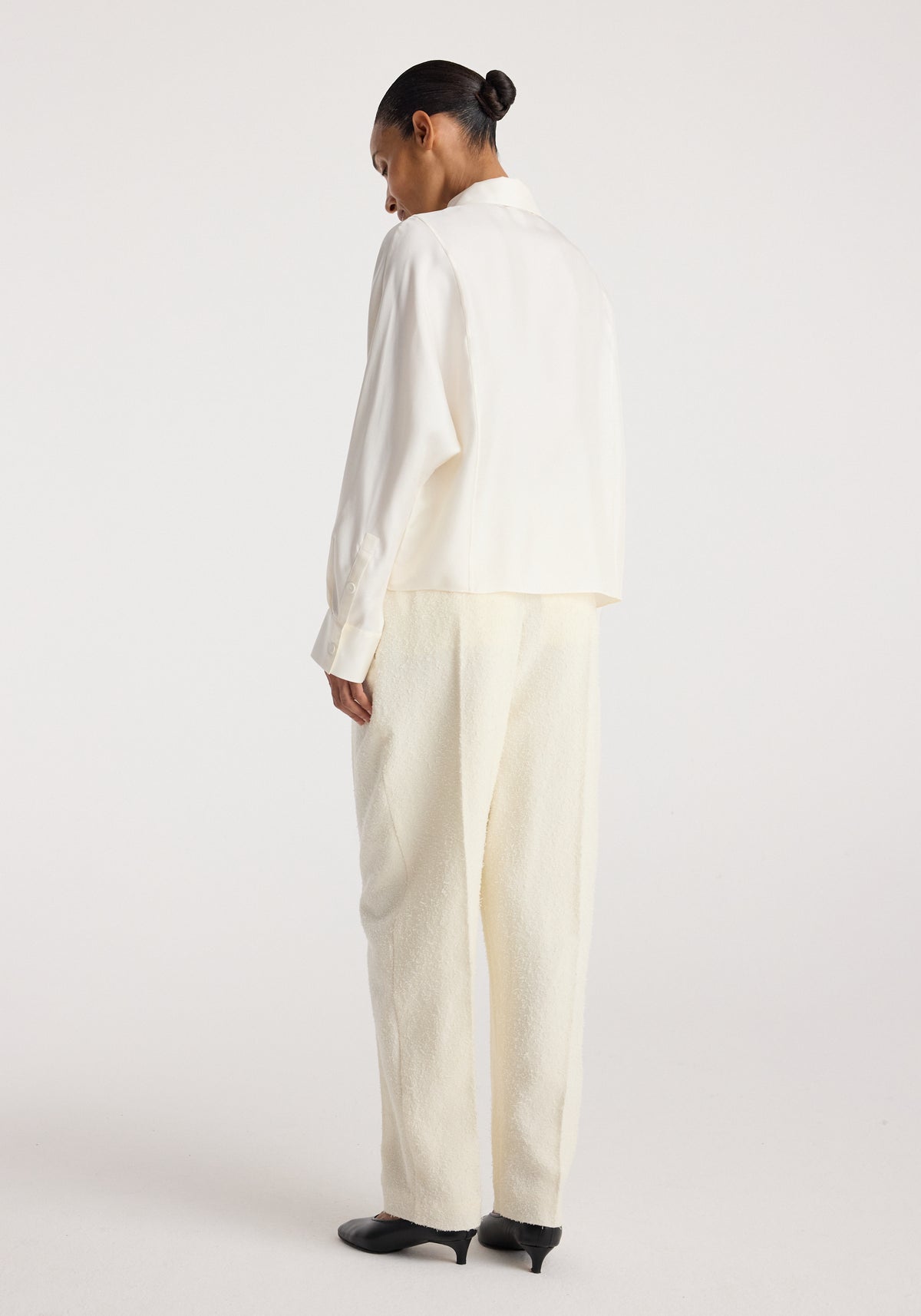 Model shown from the back wearing the Double breasted silk top | cream with matching wide leg trousers and black heels
