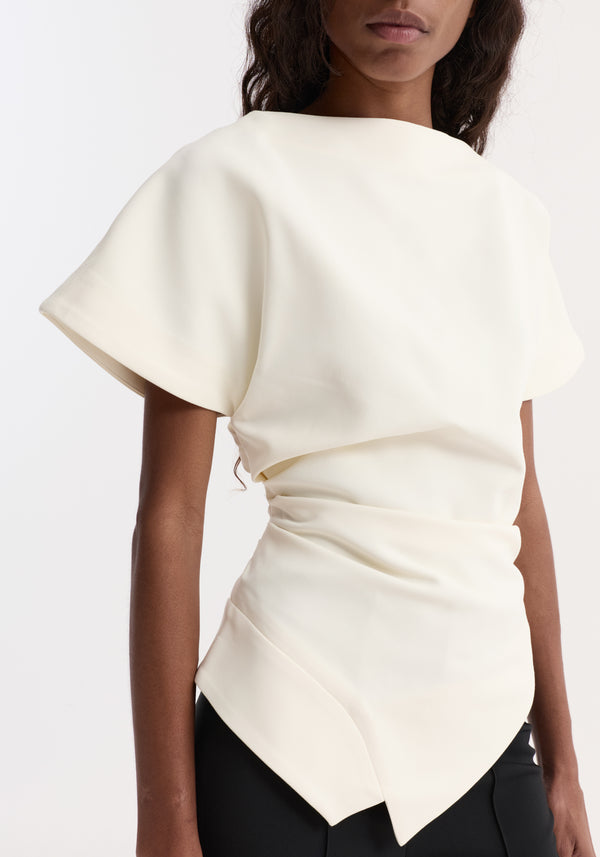 Draped lapel top | off white, features a high neckline, cap sleeves, cinched waist, asymmetrical hem, showcasing a sculptural silhouette with soft architectural design.