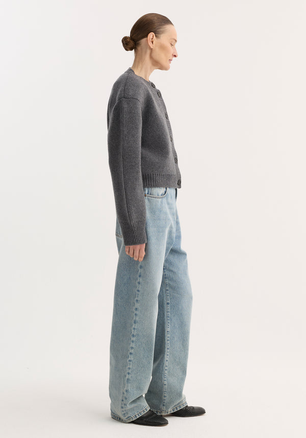 Model in sculptural Statement shoulder cardigan | mid grey melange featuring sharp shoulders, oversized fit, and ribbed details, paired with wide-leg jeans and slip-on flats.