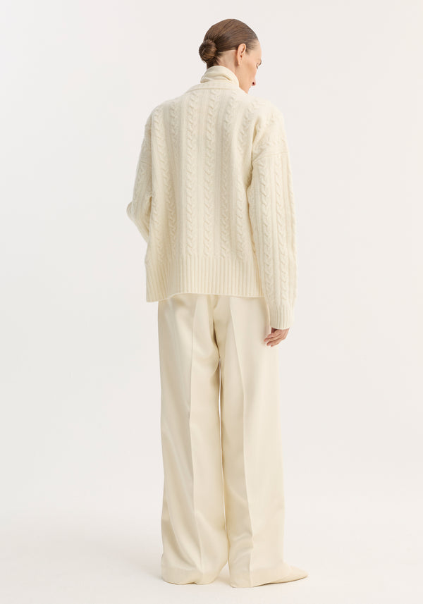 Person wearing Relaxed drawstring satin trousers in cream, featuring a wide-leg silhouette, drawstring waistband, and back welt pockets, styled with a matching cable-knit sweater.