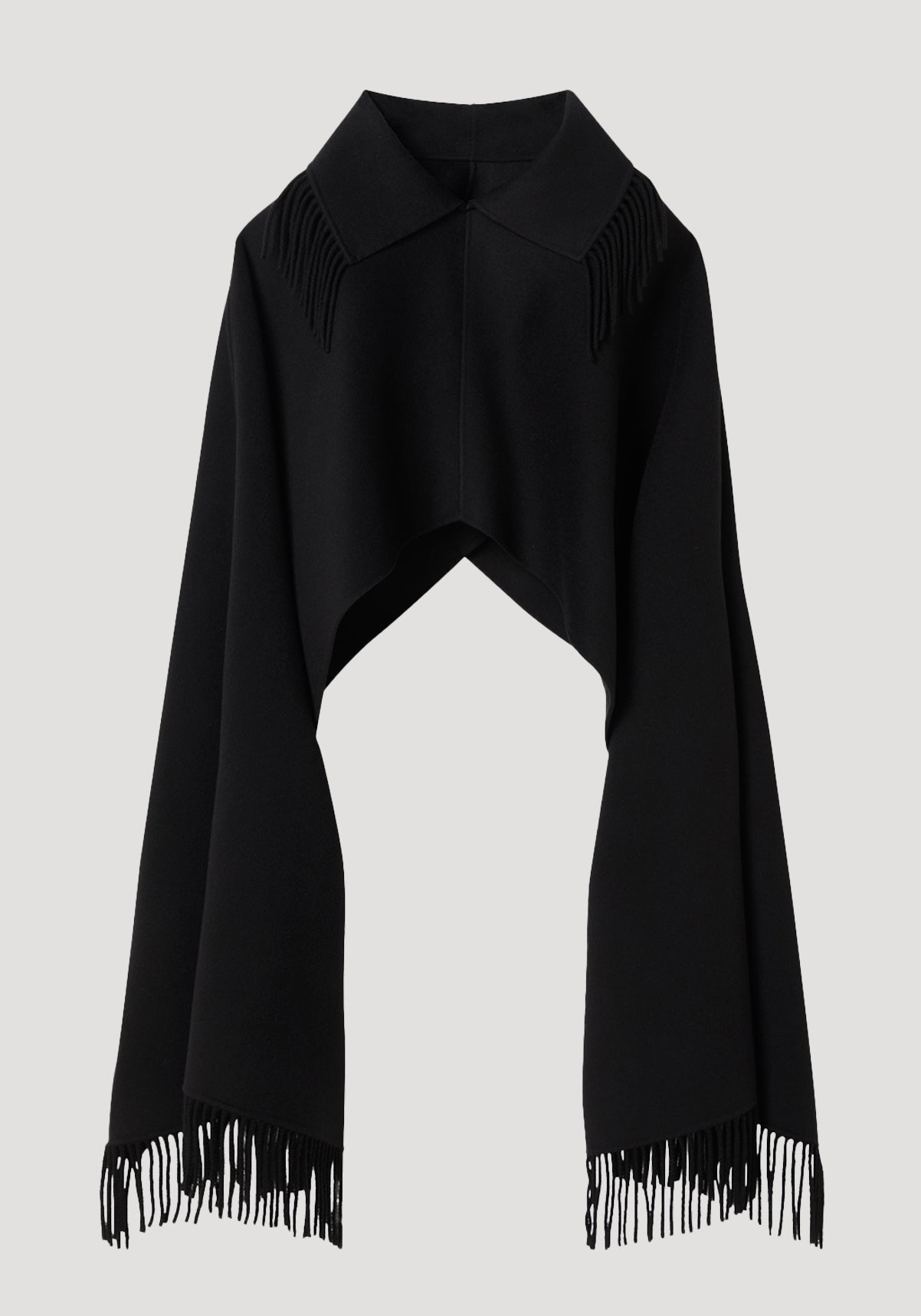 Fringe poncho double-faced wool | black, featuring a pointed collar and long fringed edges, drapes elegantly as a refined, sculptural layering piece.