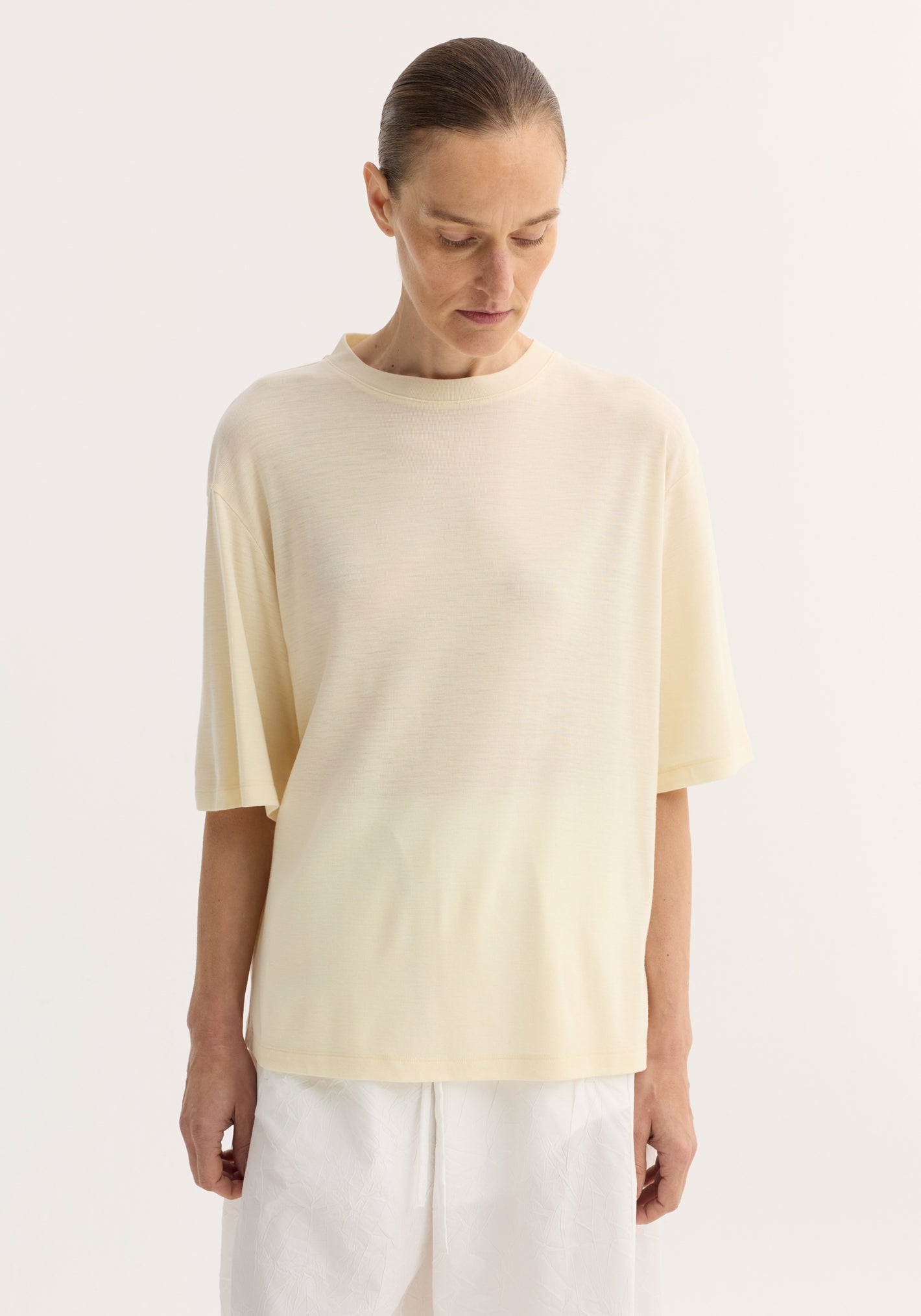 Woman wearing an oversized merino t-shirt with dropped shoulders and elbow-length sleeves, paired with drawstring-waist trousers, showcasing a relaxed, luxurious fit.