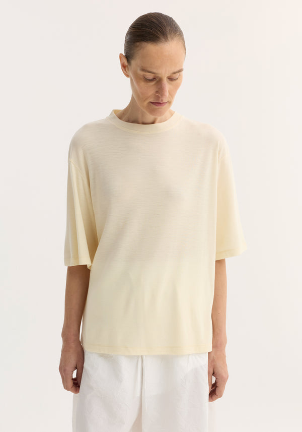 Woman wearing an oversized merino t-shirt with dropped shoulders and elbow-length sleeves, paired with drawstring-waist trousers, showcasing a relaxed, luxurious fit.