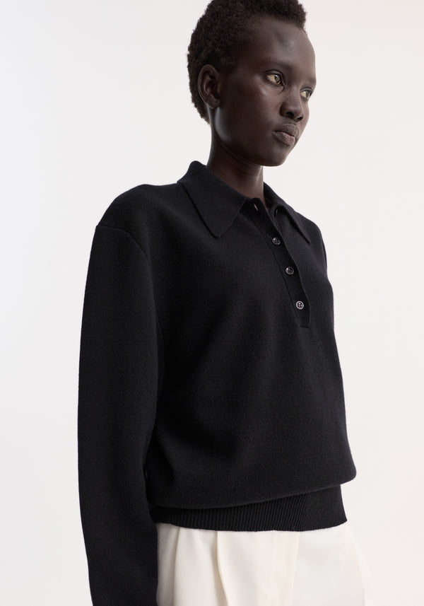 Compact knitted polo in wool-cashmere blend, featuring a structured collar, three-button placket, and rounded drop shoulders, worn by a model in white bottoms.