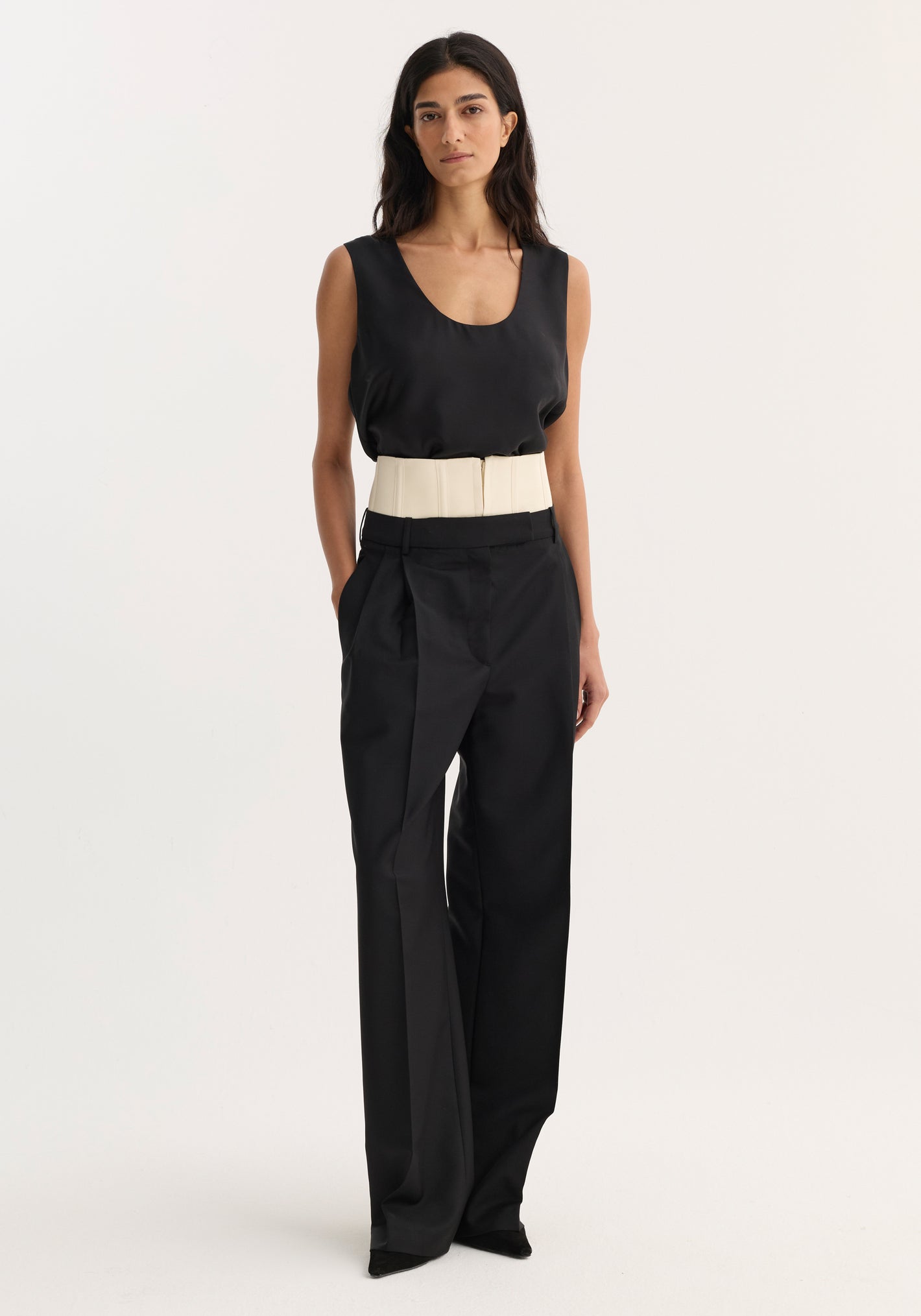 Woman wearing Corset trousers | black with a sleeveless top, featuring a structured cream belt. The tailored, wide-leg pants highlight the corset detail above the waistband.