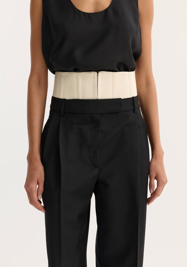 Person wearing Corset trousers | black featuring high-waisted design with a structured, boned corset detail above traditional waistband, hands resting by their sides.