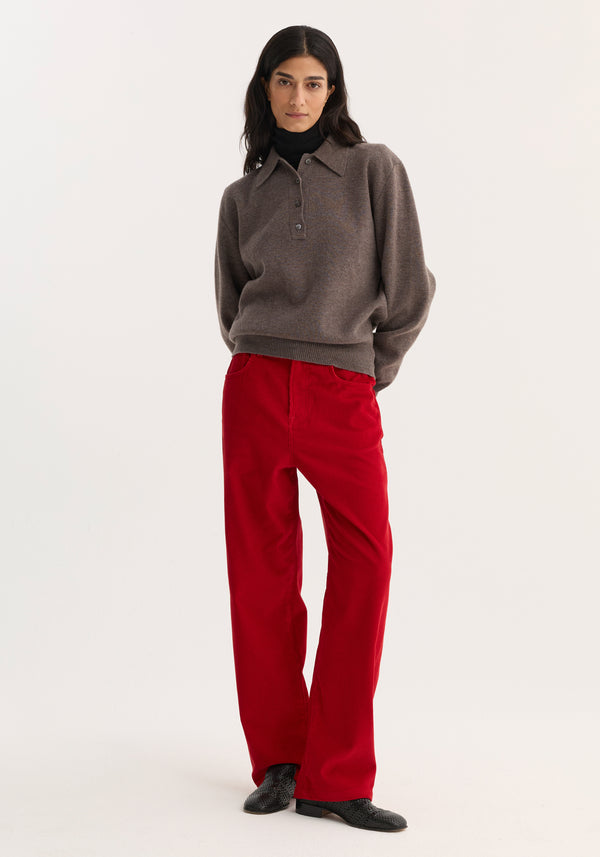Model wearing Relaxed Corduroy Trousers in Rosso, styled with a charcoal-brown sweater and black turtleneck, showcasing a casual, utilitarian look.