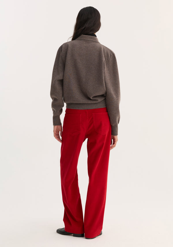 Relaxed corduroy trousers in vibrant red, wide-leg with patch pockets, styled with a brownish-gray sweater, highlighting the trousers' contrast and texture.