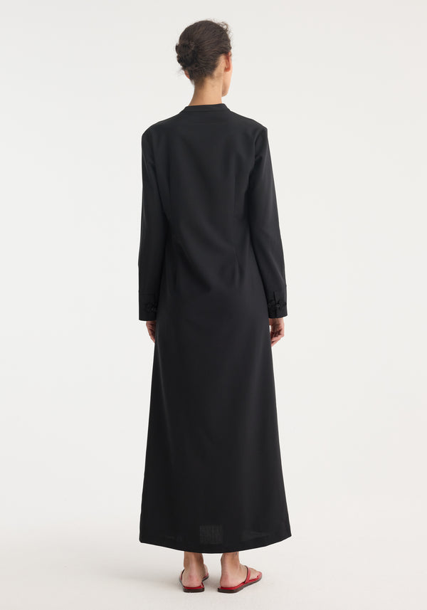 Pankou closure dress | black: Back view of a woman in a floor-length, long-sleeve dress with asymmetrical pankou closures and side split, hair in bun, red sandals.