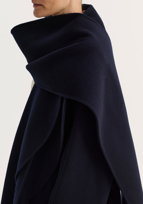Signature double-faced scarf coat in navy, featuring a double-layered scarf collar, double-breasted closure, and tailored long silhouette, draped elegantly over shoulders.