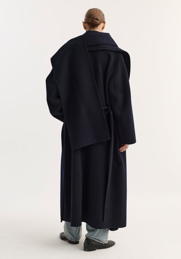 Model in navy Signature double-faced scarf coat, showcasing its elegant drape and tailored silhouette, paired with straight-leg jeans and black slip-on shoes.