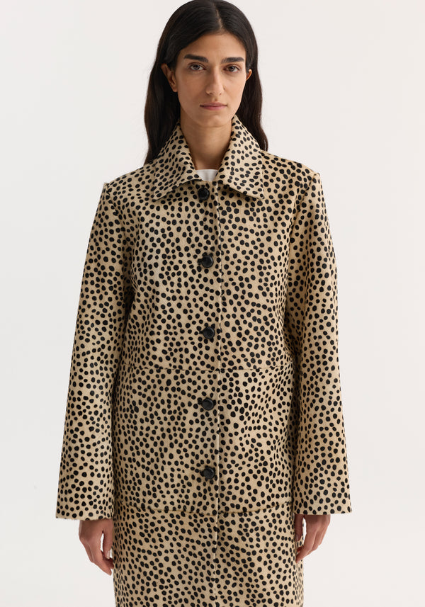 Model wearing knee-length Pony hair coat in cheetah-print with leather-knotted buttons, pointed collar, and full sleeves, showcasing a structured silhouette.