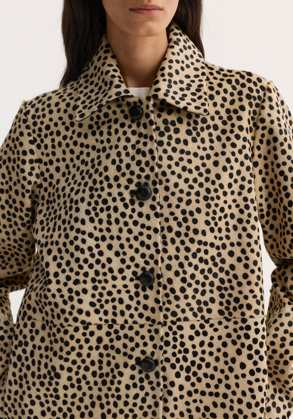 Pony hair coat in cheetah print with leather-knotted buttons, pointed collar, and side-seam pockets, showcasing a structured silhouette.