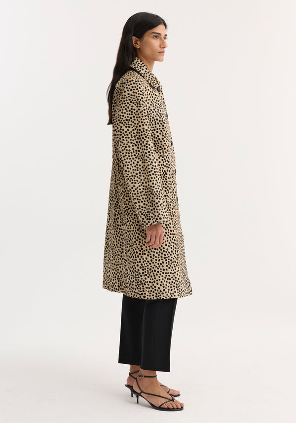 Pony hair coat | cheetah: Woman in profile wearing a cheetah-print coat with leather button closures, straight-leg trousers, and black heeled sandals.
