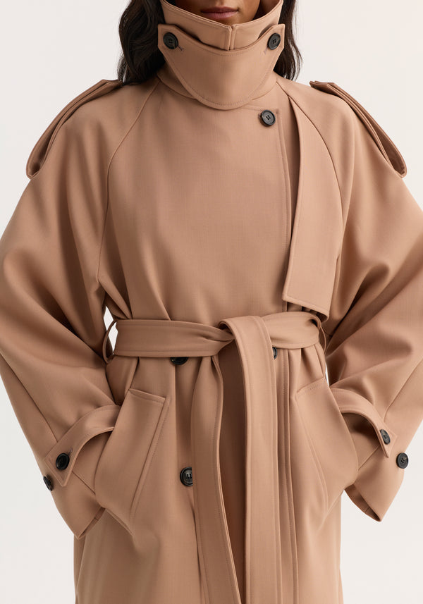 Close-up of a camel-colored Oversized Classic Trench coat with stand-up collar, epaulettes, fabric belt, deep pockets, and black buttons, highlighting its structured, contemporary design.