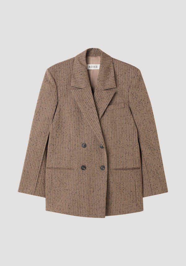 Double breasted blazer in herringbone tweed with sharp shoulders, notched lapel, four-button front, chest and welt pockets, and fine seam detailing.