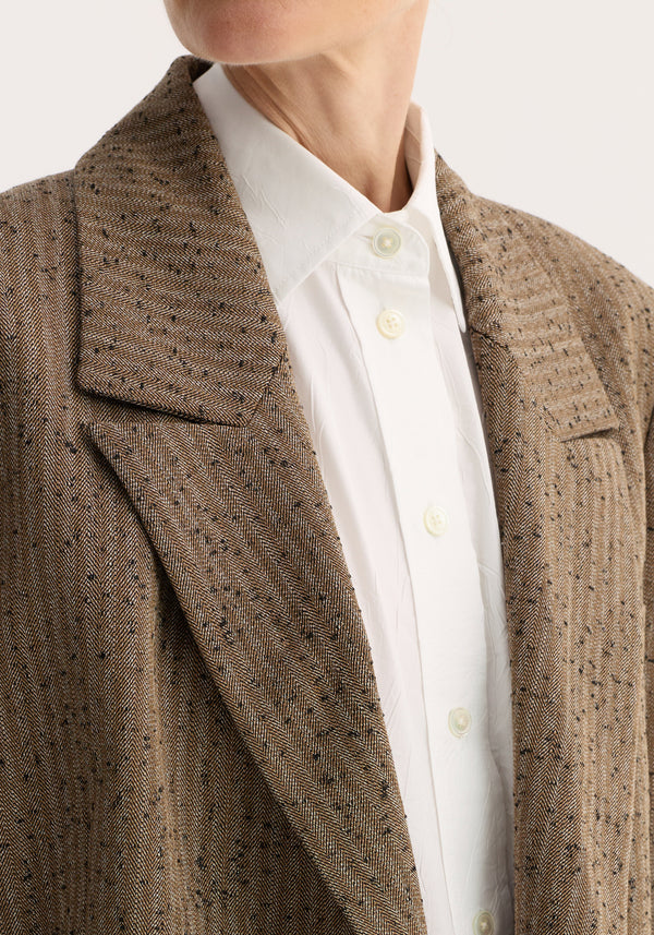 Double breasted blazer | herringbone, showcasing a crisp white shirt under a soft herringbone-textured, double-breasted blazer with welt and chest pocket detailing.