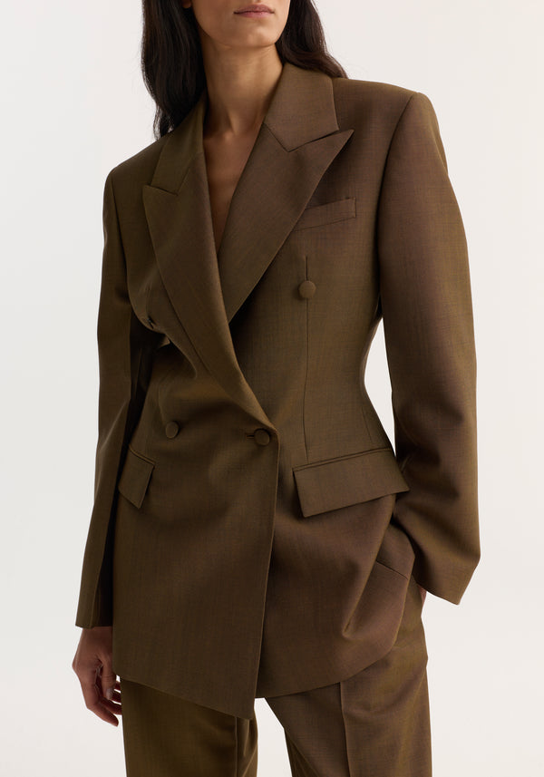 Double-breasted waisted blazer in golden brown with sharp notch lapels, padded shoulders, and flap pockets, showcasing a structured, feminine silhouette.