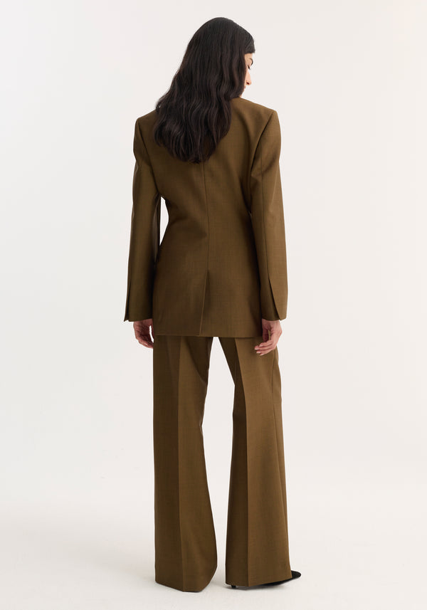 Model in an olive-brown Double-breasted waisted blazer with sharp notch lapel and strong shoulders, paired with matching high-waisted trousers, viewed from behind.