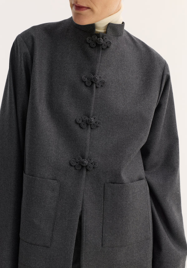 Mandarin jacket in dark grey melange with a stand collar, pankou closure, and patch pockets, worn over a light turtleneck. Virgin wool, size 36.