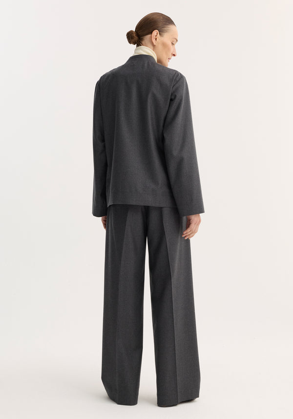 Woman in a dark grey melange Mandarin jacket with pankou closure and patch pockets, paired with wide-leg trousers, viewed from behind.