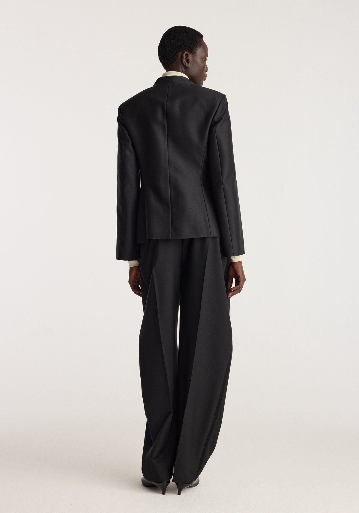 Sculptural pankou closure blazer | black shown from the back on a model with structured shoulders and a tailored silhouette paired with wide leg trousers