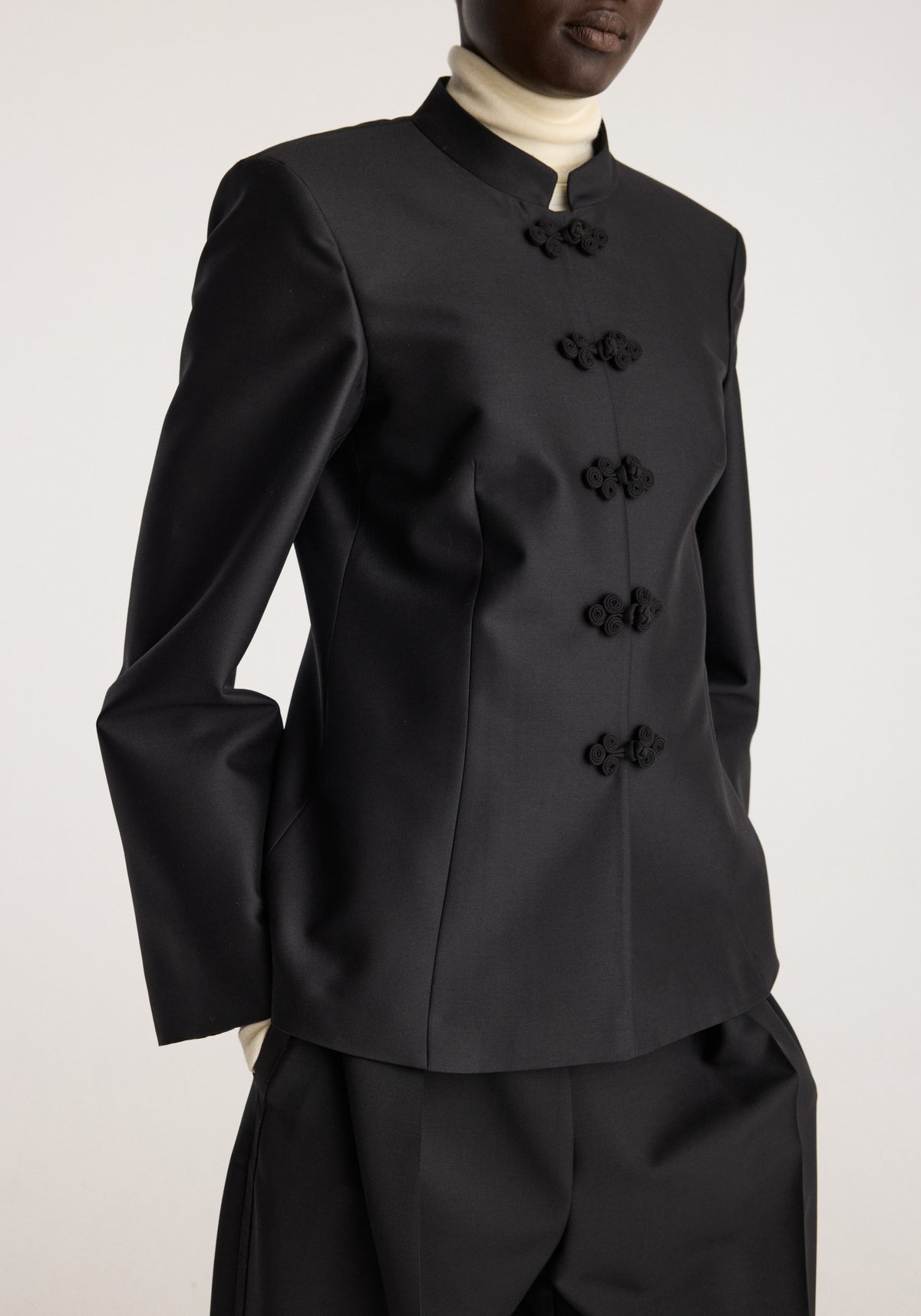 Sculptural pankou closure blazer | black worn with a cream turtleneck and black trousers showing a high collar and five decorative pankou closures
