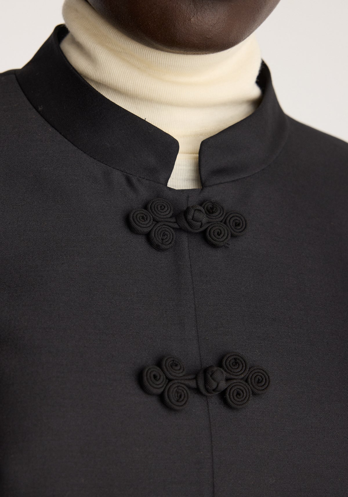 Sculptural pankou closure blazer | black shown in close up with a stand collar and two decorative knot closures over a cream turtleneck