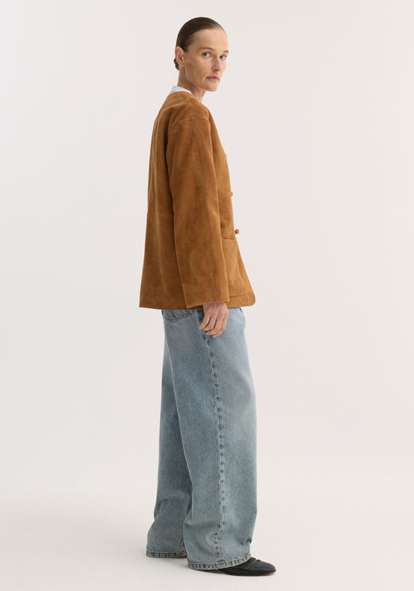 Mandarin textured suede jacket | cognac in profile, featuring a pankou closure, embroidered edges, and patch pockets, worn over a white top with light-wash jeans.