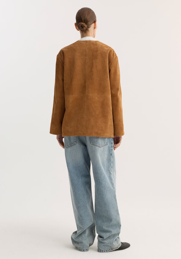 Mandarin textured suede jacket in cognac with pankou closure and patch pockets, worn with loose-fit light-wash jeans, highlighting its refined artisanal style.