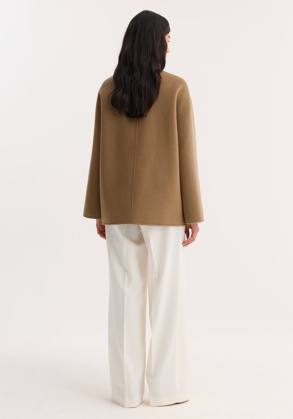 Person wearing Mandarin double-faced wool jacket with embroidered edges and patch pockets, standing with back to camera, paired with wide-leg trousers.