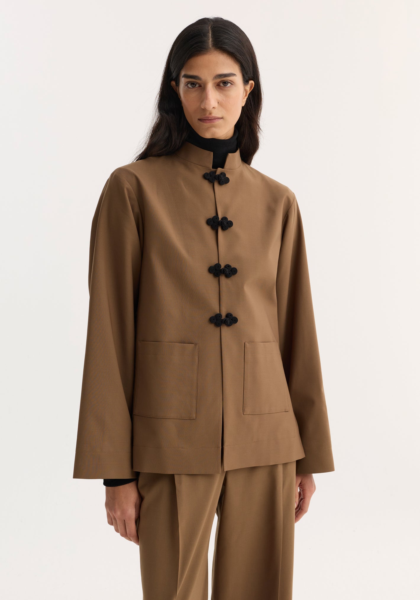 Model in Róhe 'Marie' Mandarin Jacket with pankou closures, patch pockets, and wide sleeves, paired with loose-cut trousers, showcasing a flowing, elegant silhouette.