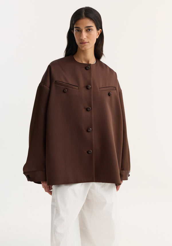 Model in Western heavy satin jacket | espresso, featuring oversized fit, leather-knotted buttons, chest welt pockets, paired with wide-leg trousers for a minimalist style.