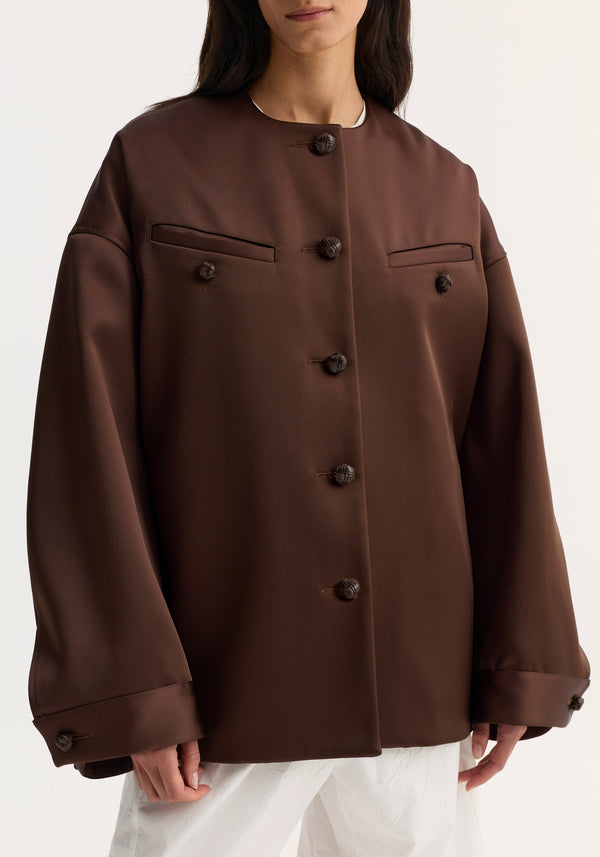 Western heavy satin jacket in espresso, featuring oversized fit, leather-knotted button closures, rounded sleeves, chest welt pockets, and a relaxed silhouette.