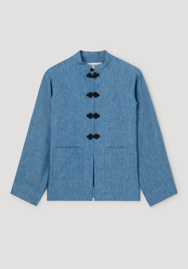 Mandarin jacket in ocean blue with black frog closures, patch pockets, and embroidered edges. Made from 100% linen, showcasing a soft, washed delavé finish.
