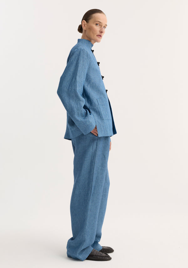 Person in profile wearing Mandarin jacket | ocean blue with pankou closures and patch pockets, paired with matching wide-leg trousers and black slip-on shoes.